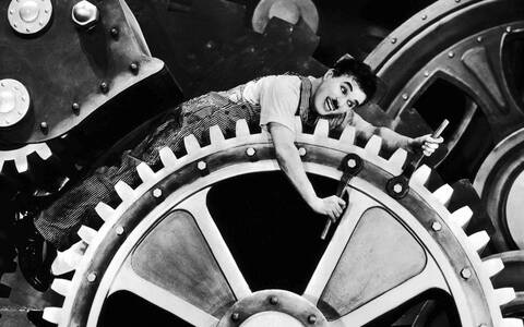 A sequência em que Chaplin fica preso nas engrenagens é o ápice iconográfico (Foto: Wiki) A sequência em que Chaplin fica preso nas engrenagens é o ápice iconográfico (Foto: Wiki)